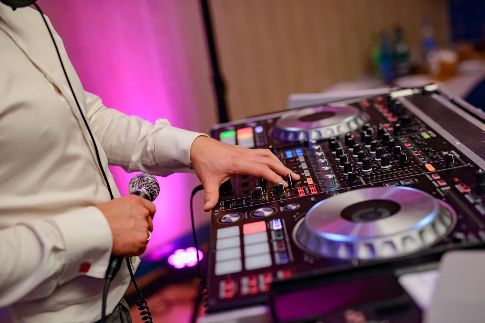 DJ mixing live with microphone in hand at an evening reception
