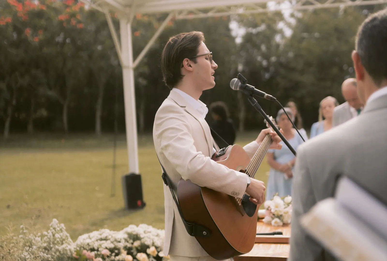 Acoustic guitarist and singer performing during an outdoor wedding ceremony