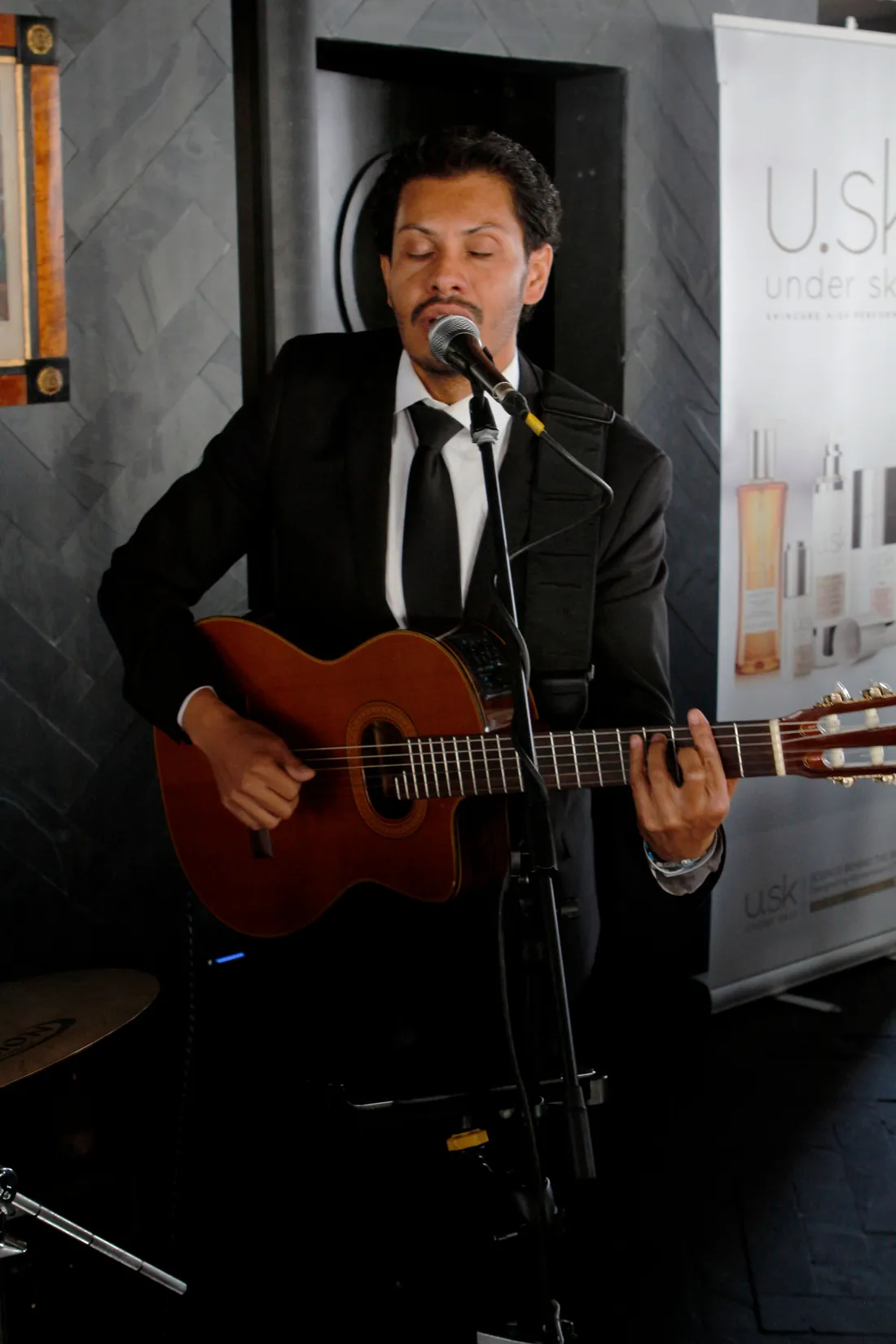 Suited singer-guitarist performing at a branded corporate event