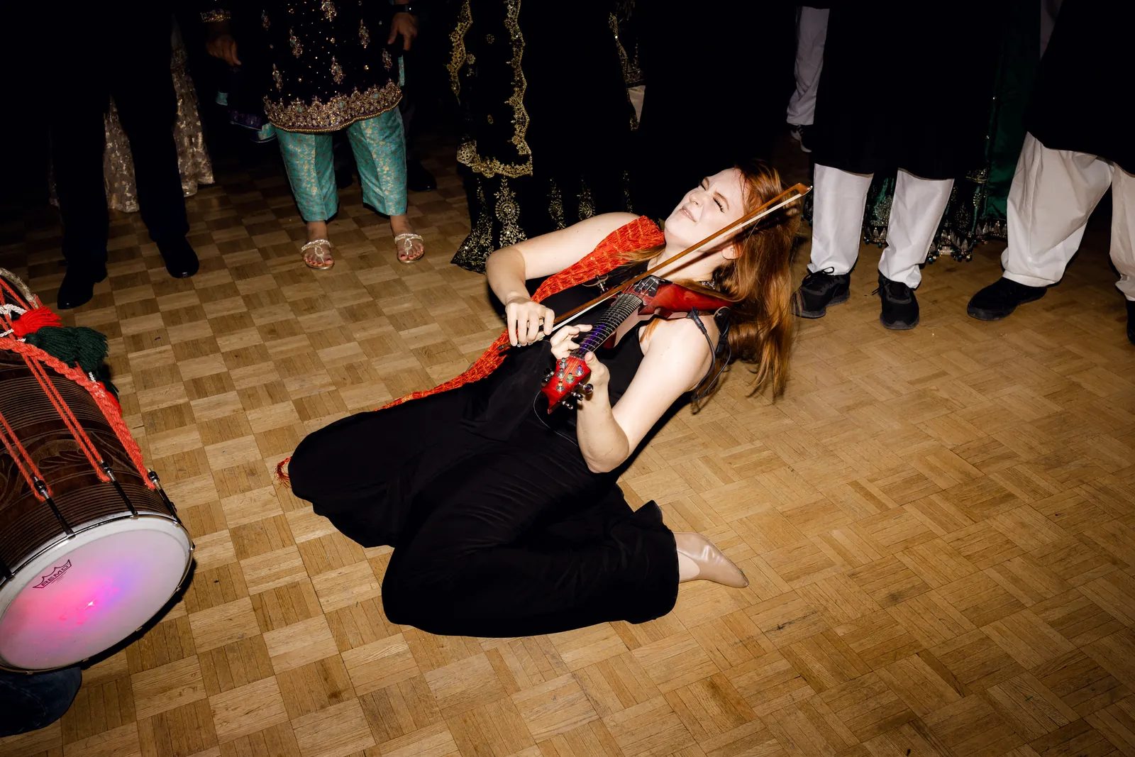Electric violinist performing on the dance floor beside a dhol drummer at a wedding reception