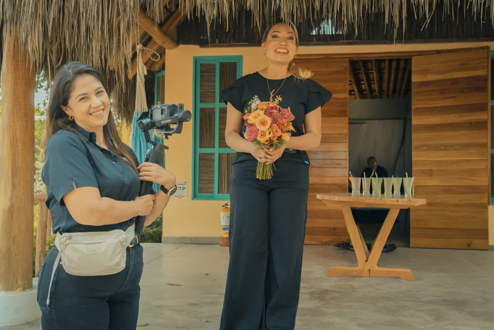 Videographer filming a smiling bride holding her bouquet before an outdoor wedding ceremony